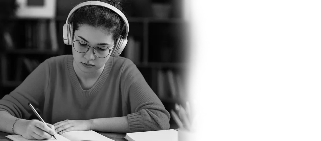 Student girl wearing headphones and glasses writing notes in her notebook while listening to lo-fi study beats from Lofi Mind Melody